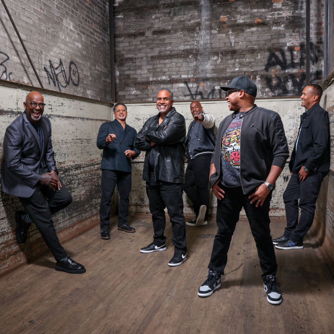 members of take six standing in a room and smiling,