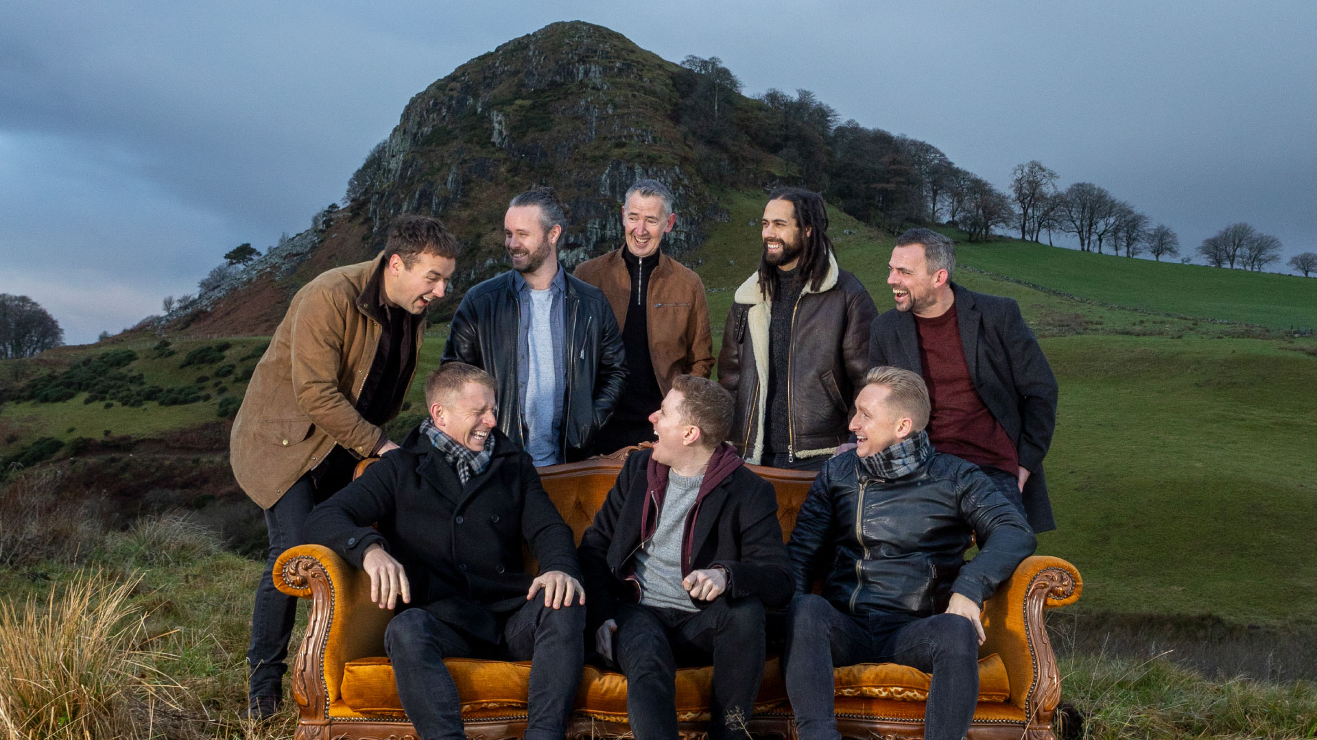 the members of the band skerryvore pose by a couch outside with a view of scottish highlands behind them