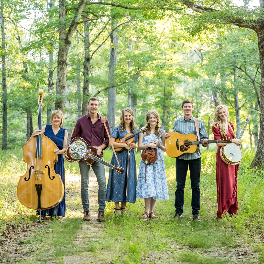 An Evening With the Petersens - an image of the band standing with their instruments in the sunny forest