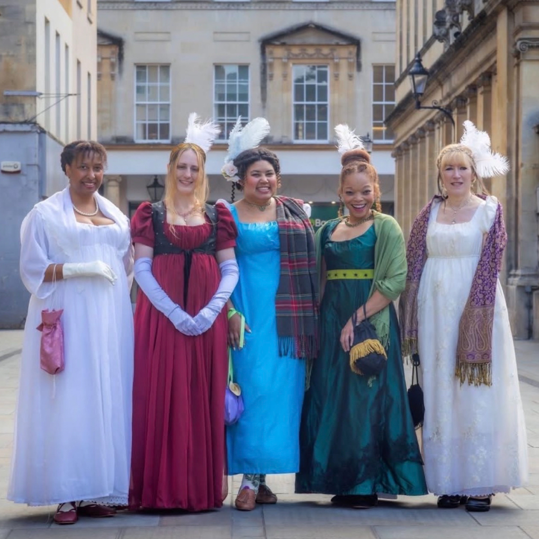 a group of five women wearing regency era costumes in a european city
