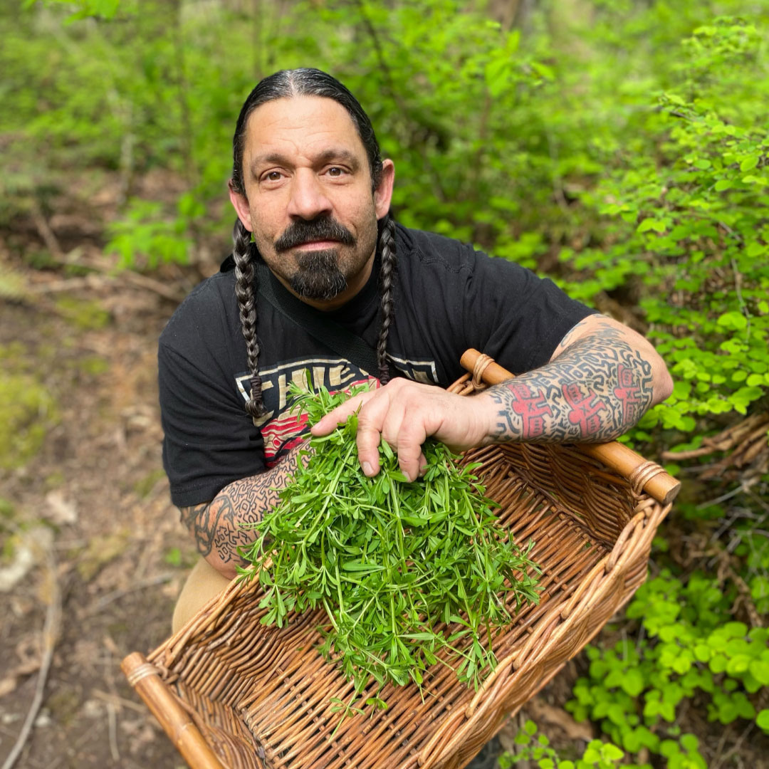Indigenous chef Jason Vickers holds a basket of greens out in the garden